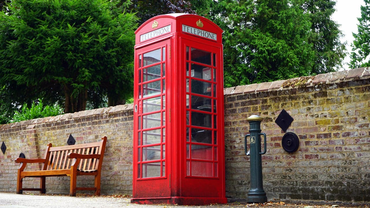 Red telephone booth in front of a brick wall