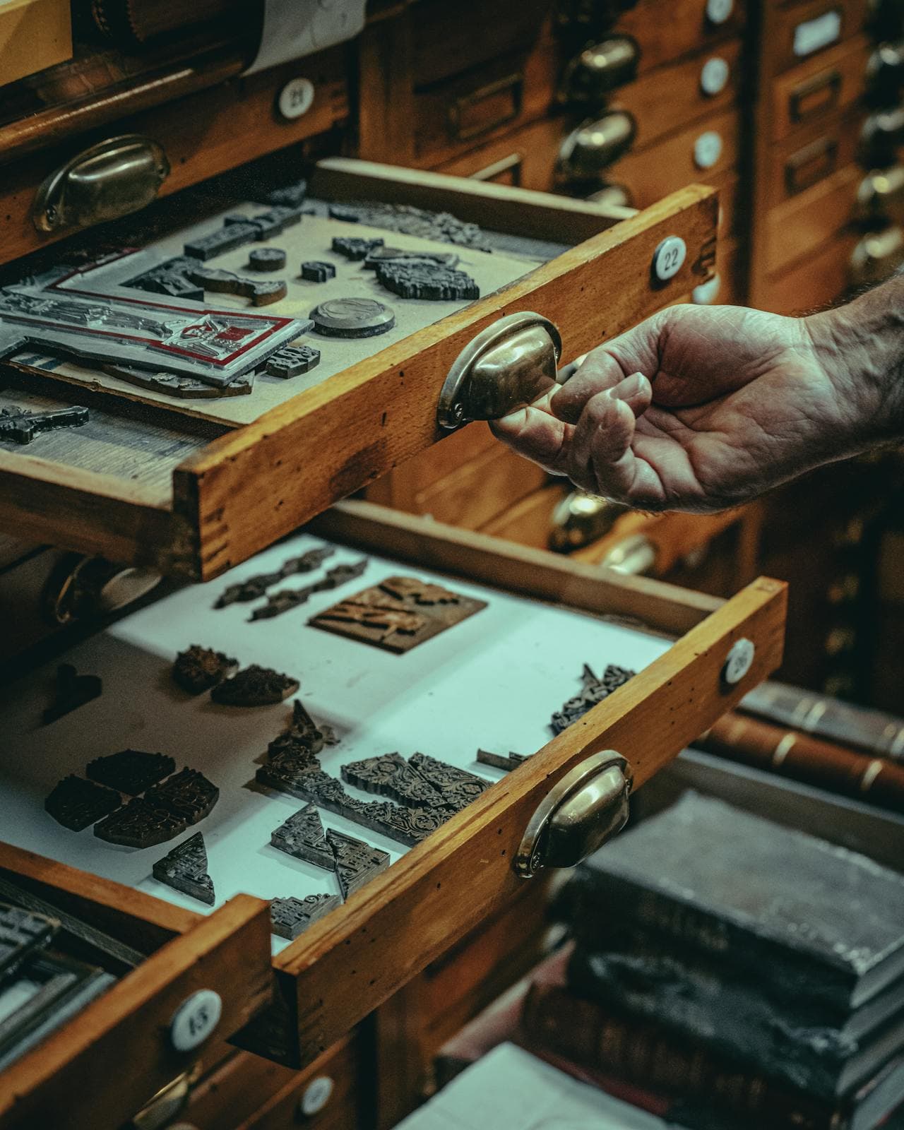 Old artisan showing vintage and antique artifacts in wooden drawers